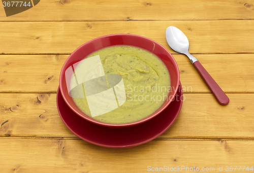 Image of Full bowl of green soup with a spoon