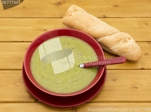 Image of Bowl of pea and ham soup with a baguette