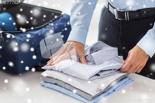 Image of businessman packing clothes into travel bag