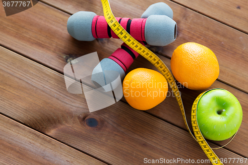 Image of close up of dumbbell, fruits and measuring tape