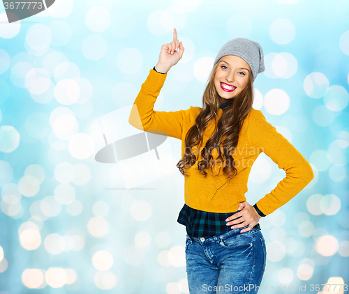 Image of happy young woman or teen girl pointing finger up