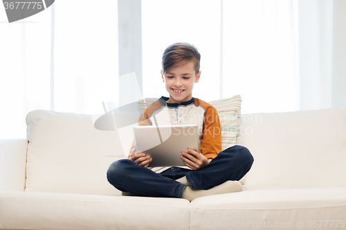 Image of smiling boy with tablet computer at home