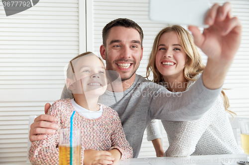 Image of happy family taking selfie at restaurant