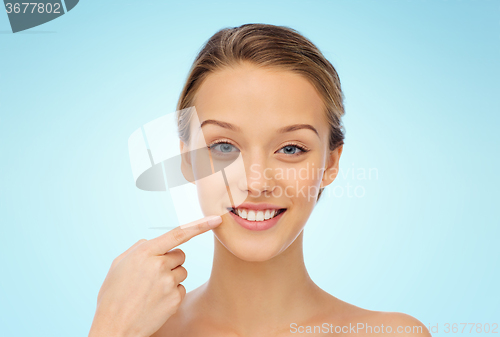 Image of happy young woman pointing finger to her smile