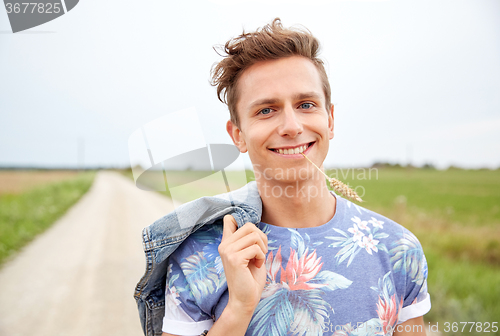 Image of smiling young hippie man on country road