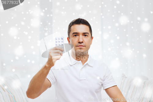 Image of man showing pack of pills at home
