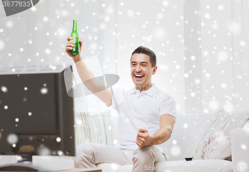 Image of smiling man watching tv and drinking beer at home