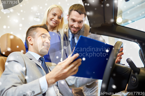 Image of happy couple with car dealer in auto show or salon