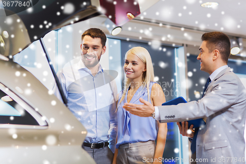 Image of happy couple with car dealer in auto show or salon