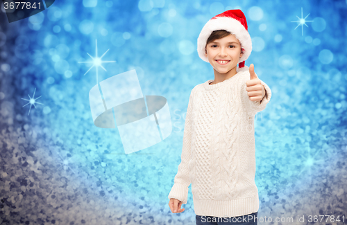 Image of smiling happy boy in santa hat showing thumbs up