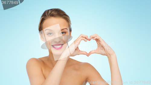 Image of smiling young woman showing heart shape hand sign