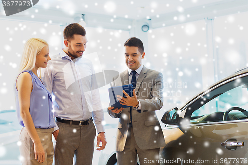 Image of happy couple with car dealer in auto show or salon