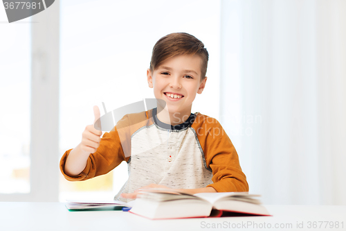 Image of happy student boy with textbook showing thumbs up