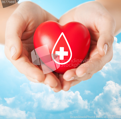 Image of female hands holding red heart with donor sign