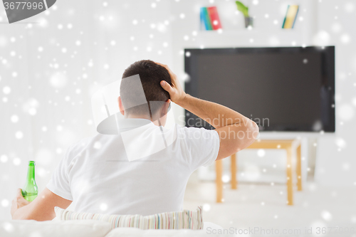 Image of man watching tv and drinking beer at home