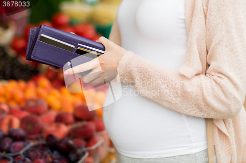 Image of pregnant woman with wallet buying food at market