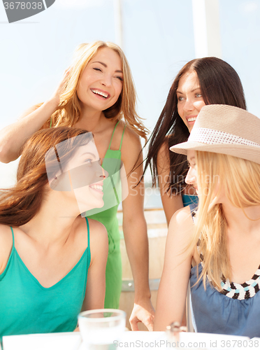 Image of group of smiling girls in cafe on the beach