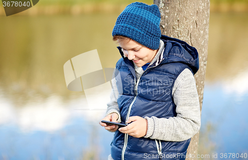 Image of happy boy playing game on smartphone outdoors