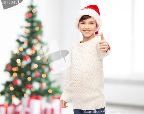 Image of smiling happy boy in santa hat showing thumbs up