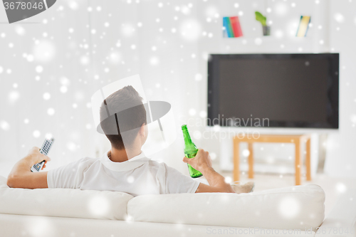 Image of man watching tv and drinking beer at home