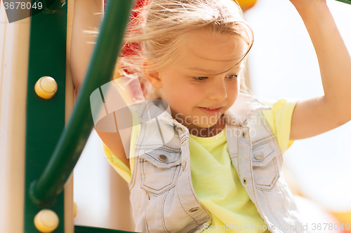 Image of happy little girl climbing on children playground