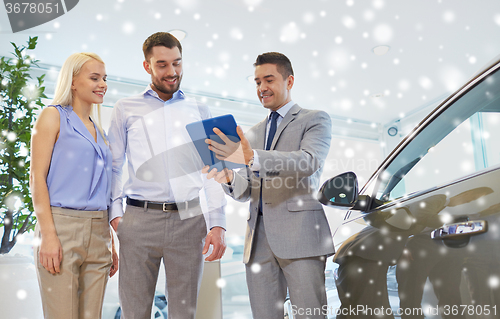 Image of happy couple with car dealer in auto show or salon