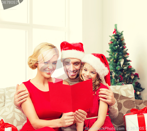 Image of happy family in santa hats with greeting card