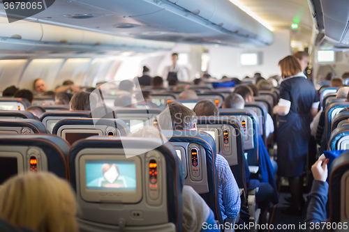 Image of Stewardessand passengers on commercial airplane.