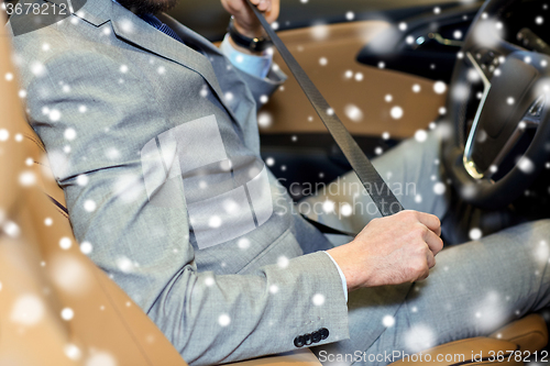 Image of close up of man fastening seat safety belt in car