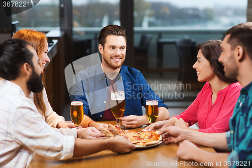 Image of friends eating pizza with beer at restaurant