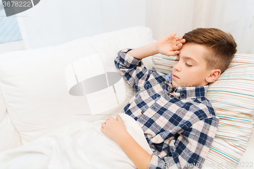 Image of ill boy lying in bed and suffering from headache