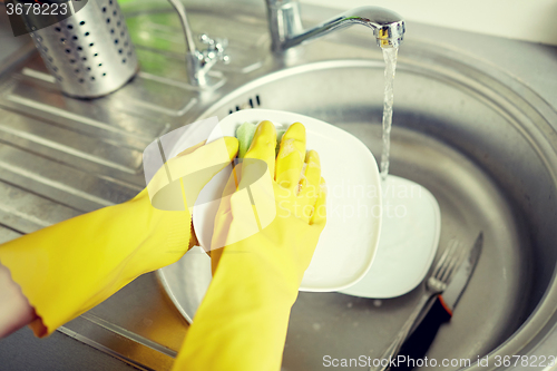 Image of close up of woman hands washing dishes in kitchen