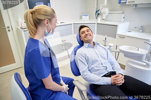 Image of happy female dentist with man patient at clinic