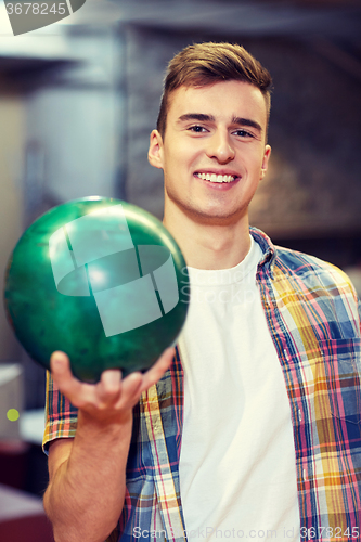 Image of happy young man holding ball in bowling club