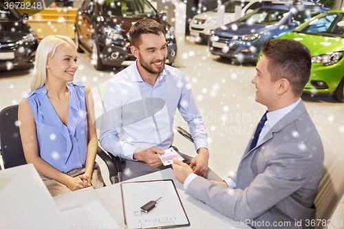 Image of happy couple with car dealer in auto show or salon