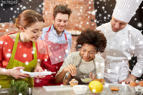 Image of happy friends and chef cook baking in kitchen