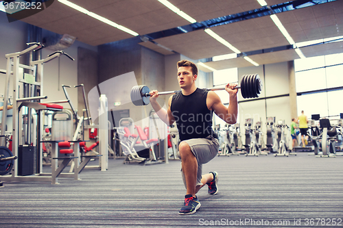 Image of young man flexing muscles with barbell in gym