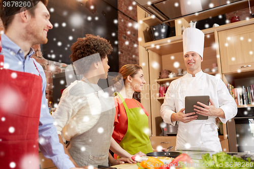 Image of happy friends with tablet pc in kitchen