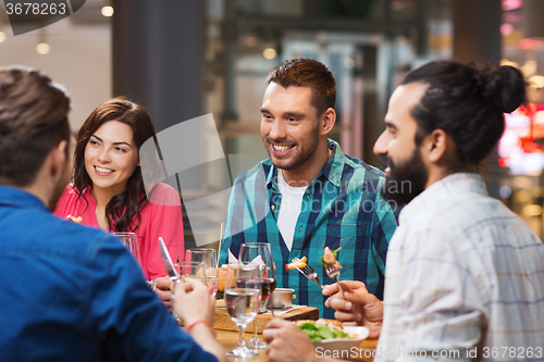 Image of happy friends having dinner at restaurant