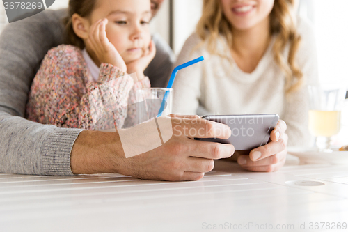 Image of close up of family with smartphone at restaurant