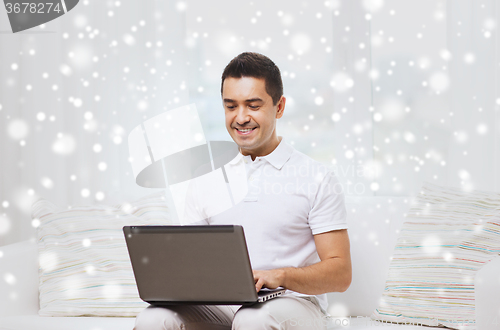 Image of happy man working with laptop computer at home