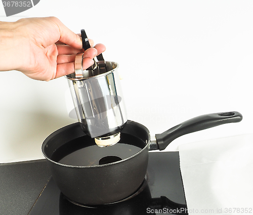 Image of Baker making donuts with a squeeze container into hot oil in sma