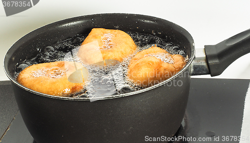 Image of Donuts cooking in boiling oil in kettle