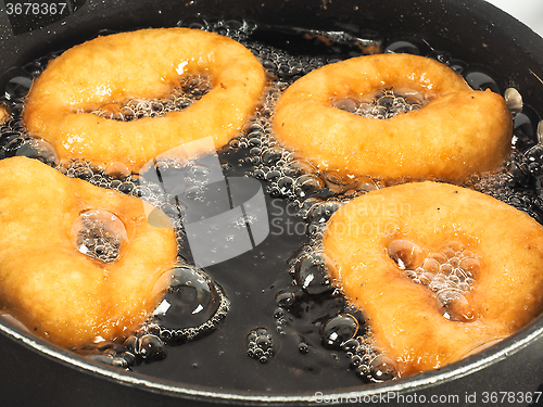 Image of Closeup of doughnuts boiling in kettle of oil