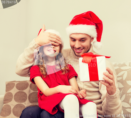 Image of smiling father surprises daughter with gift box