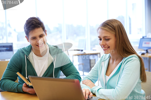 Image of happy students with laptop and books at library