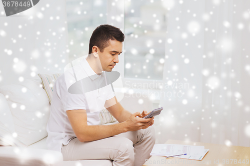 Image of man with papers and calculator at home