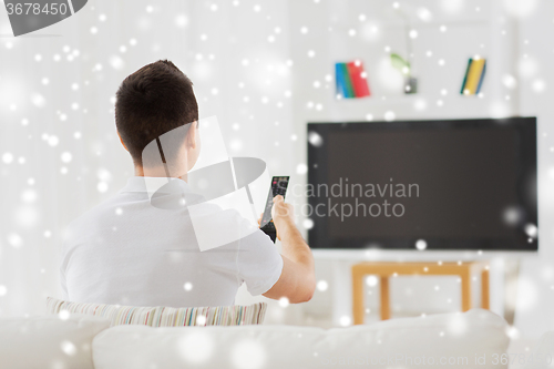 Image of man watching tv and changing channels at home