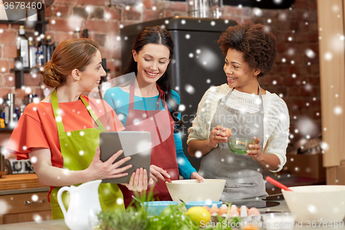 Image of happy women with tablet pc cooking in kitchen