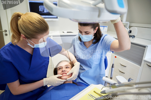 Image of happy female dentist with patient girl at clinic